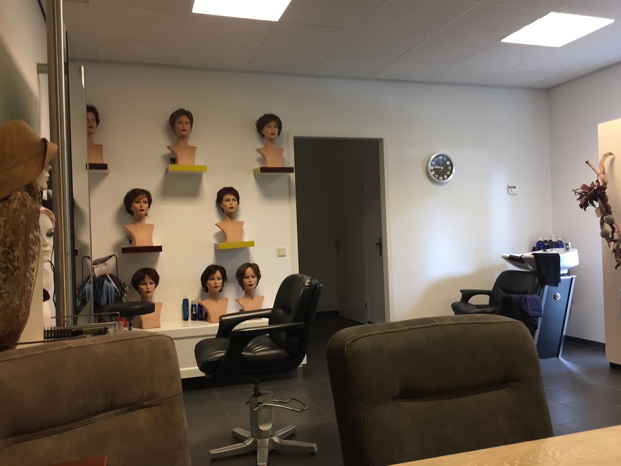 De haarwerkstudio met haarwerken op hoofdmodellen aan de wand
