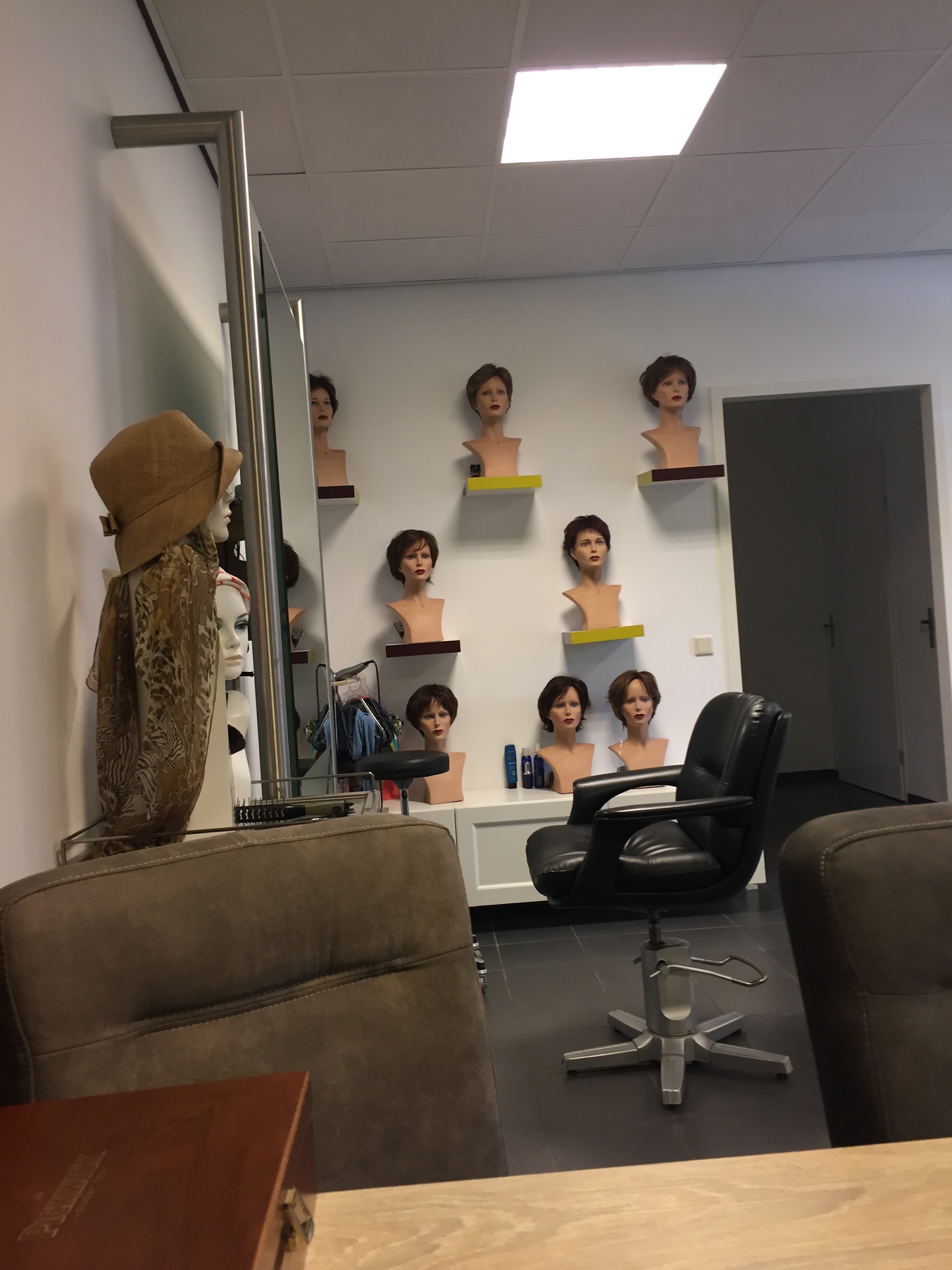 Het behandelgedeelte van de haarwerkstudio met hoofdmodellen op de planken